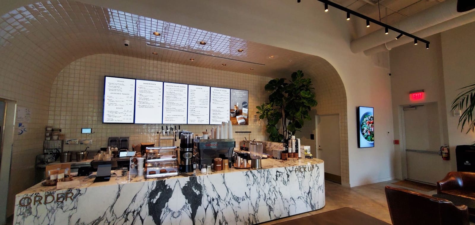 Digital menu boards above a marble cafe counter